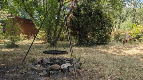 Dreibein-Grill über Feuerstelle im Garten.