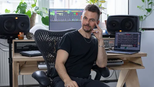 Mann sitzt im Musikstudio mit Ausrüstung.