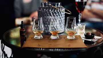 Drei Whiskygläser auf Tisch mit Dekoration.
