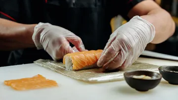 Chef preparing sushi on a counter.