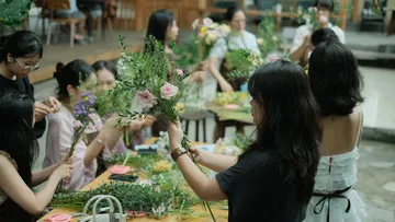 Frauen arrangieren Blumen am Tisch.