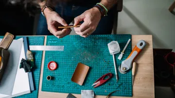 Hands crafting on a table with tools.