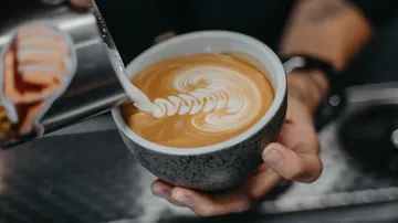 Barista gießt Latte Art in Kaffeetasse.