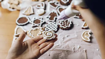 Hand decorates cookies with white icing.