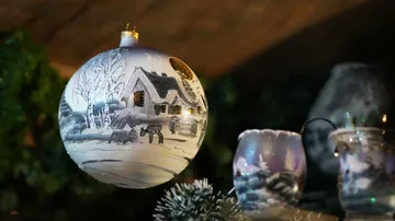 Decorated Christmas ornament hangs indoors, glowing softly.