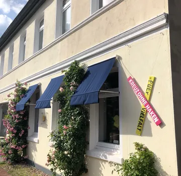 Blaue Markisen an blumenverzierter Hauswand.