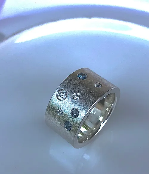 Silberring mit Edelsteinen auf Teller.