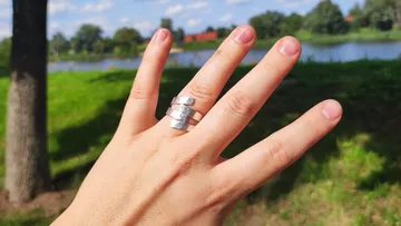 Hand trägt Silberring nahe eines Sees.