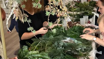 People making wreaths with green foliage.