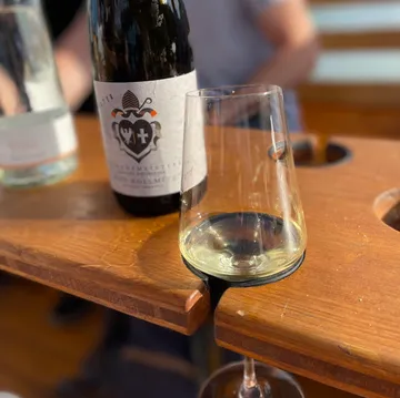 Wine glass on wooden table, bottle nearby.