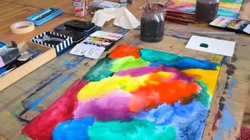 Colorful painting on a cluttered artist's desk.
