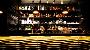 Bar mit Flaschen auf Regalen, stimmungsvolle Beleuchtung.