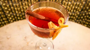 Cocktail with orange peel and cinnamon stick.