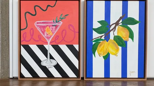 Two colorful framed paintings on a wooden floor.