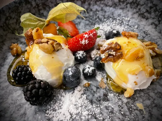 Joghurt mit Beeren und Nüssen auf Teller.