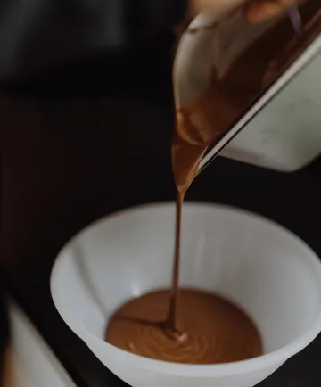 Chocolate being poured into white bowl.