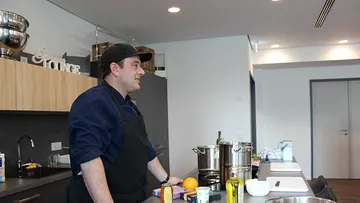 Koch in Küche mit Kochutensilien.