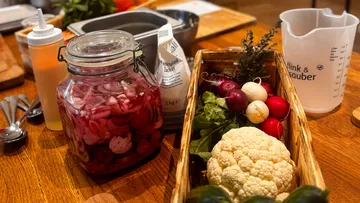 Gemüse und Glas auf Holztisch in Küche.