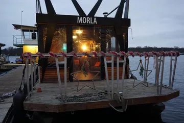 Boat named Morla docked, decorated with lights.