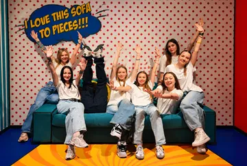 Gruppe posiert auf Sofa, spielerischer Hintergrund.