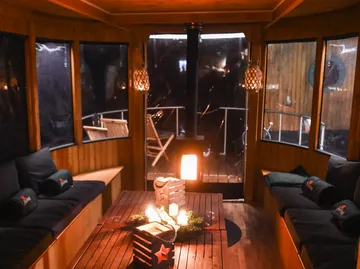 Cozy cabin with lit candles, cushions.