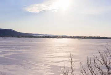 Snow-covered field under bright sky.