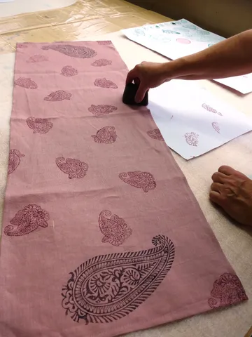 Hand blockdruckt Muster auf rosa Stoff.