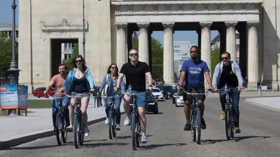 Group cycling near a historic gateway.