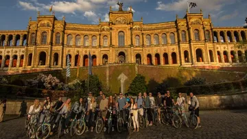Gruppe auf Fahrrädern vor historischem Gebäude.