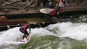 Surfer reitet Welle in städtischem Flussbereich.