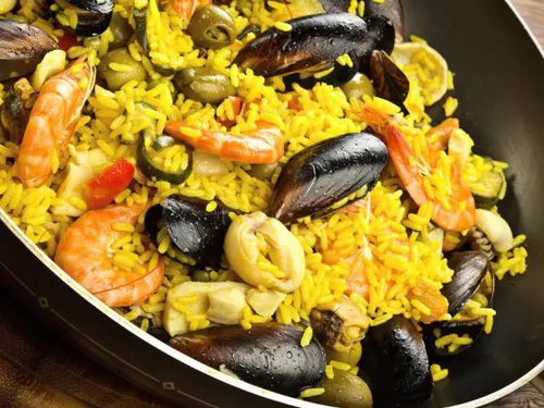 Reisgericht mit Meeresfrüchten und Gemüse in Pfanne.