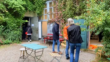 People entering garden building with open door.