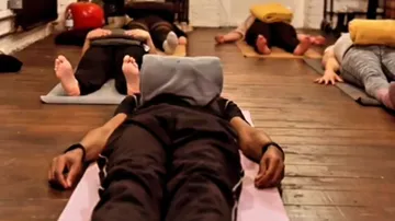 People lying on yoga mats in a studio.