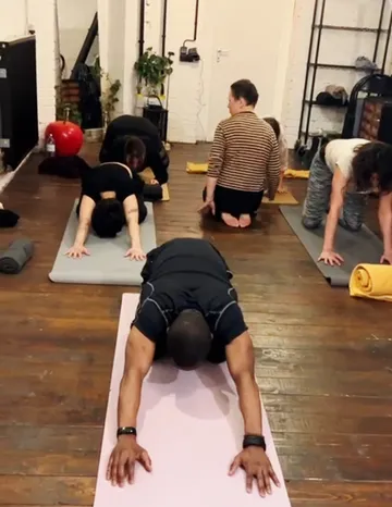 Menschen machen Yoga auf Matten drinnen.