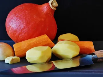 Pumpkin and vegetables lie on a black cutting board.