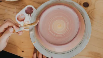 Hand painting pottery on wooden table.