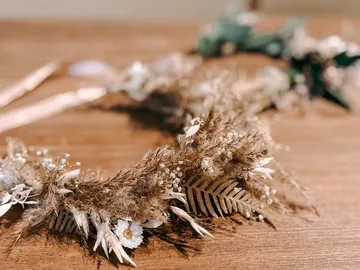 Trockenblumenkranz liegt auf einem Holztisch.