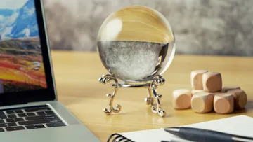 Glaskugel auf Schreibtisch mit Laptop.