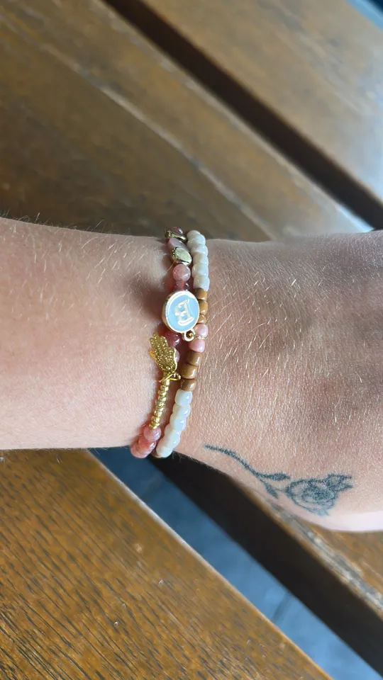 Wrist wearing bracelets on wooden table.