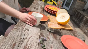 Hand einer Person stellt Becher auf Holztisch.