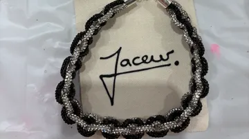 Beaded black and silver necklace on white fabric.
