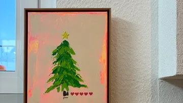 Framed Christmas tree painting in room.
