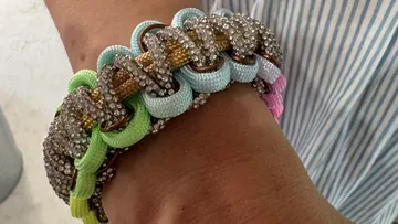 Colorful textured bracelet on wrist, striped shirt.