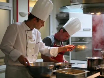 Chefs prepare various dishes in a modern kitchen.