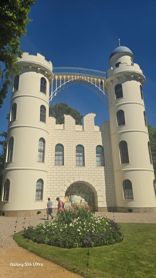 Two towers connected by bridge, garden below.