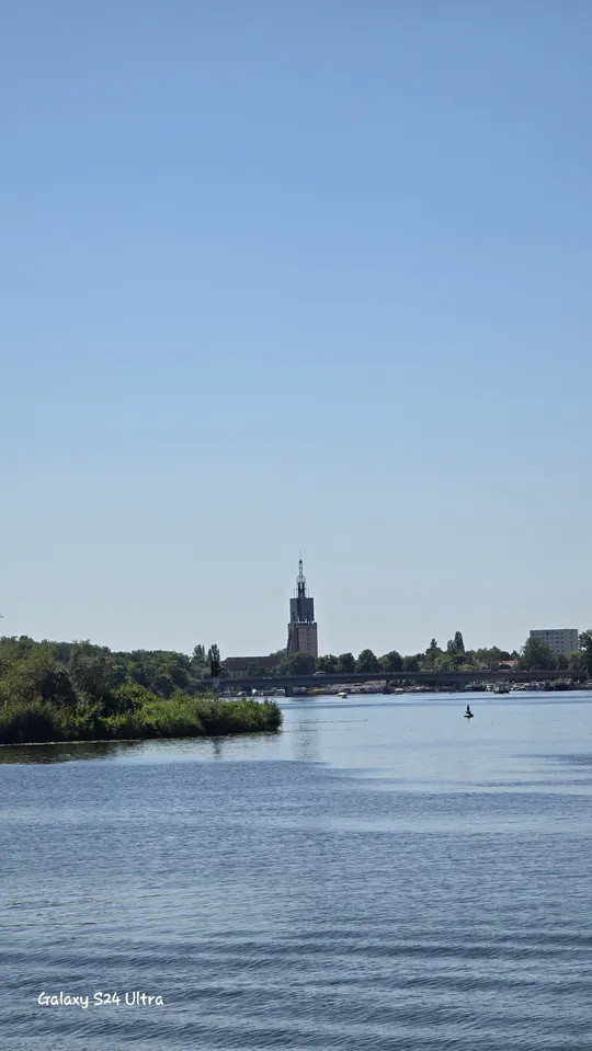 Tower rises above riverside cityscape.