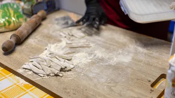 Hausgemachte Nudeln werden auf Holztisch geschnitten.