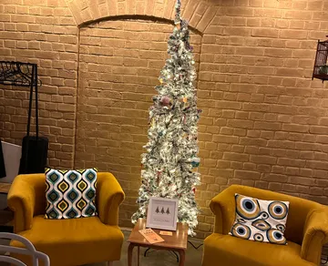 Weihnachtsbaum zwischen zwei gelben Sesseln.