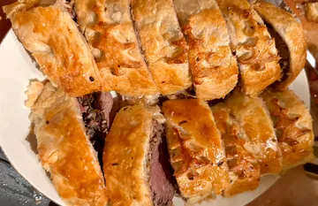 Geschnittenes Beef Wellington auf weißem Teller.