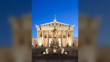 Parliament building with statue at night.